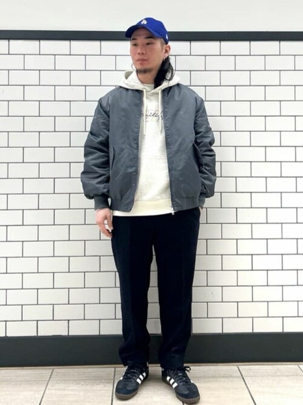 グレー系のMA-1、ホワイト系のパーカー、ブルー系のスラックスを着用したメンズの冬コーディネートの1枚目の写真