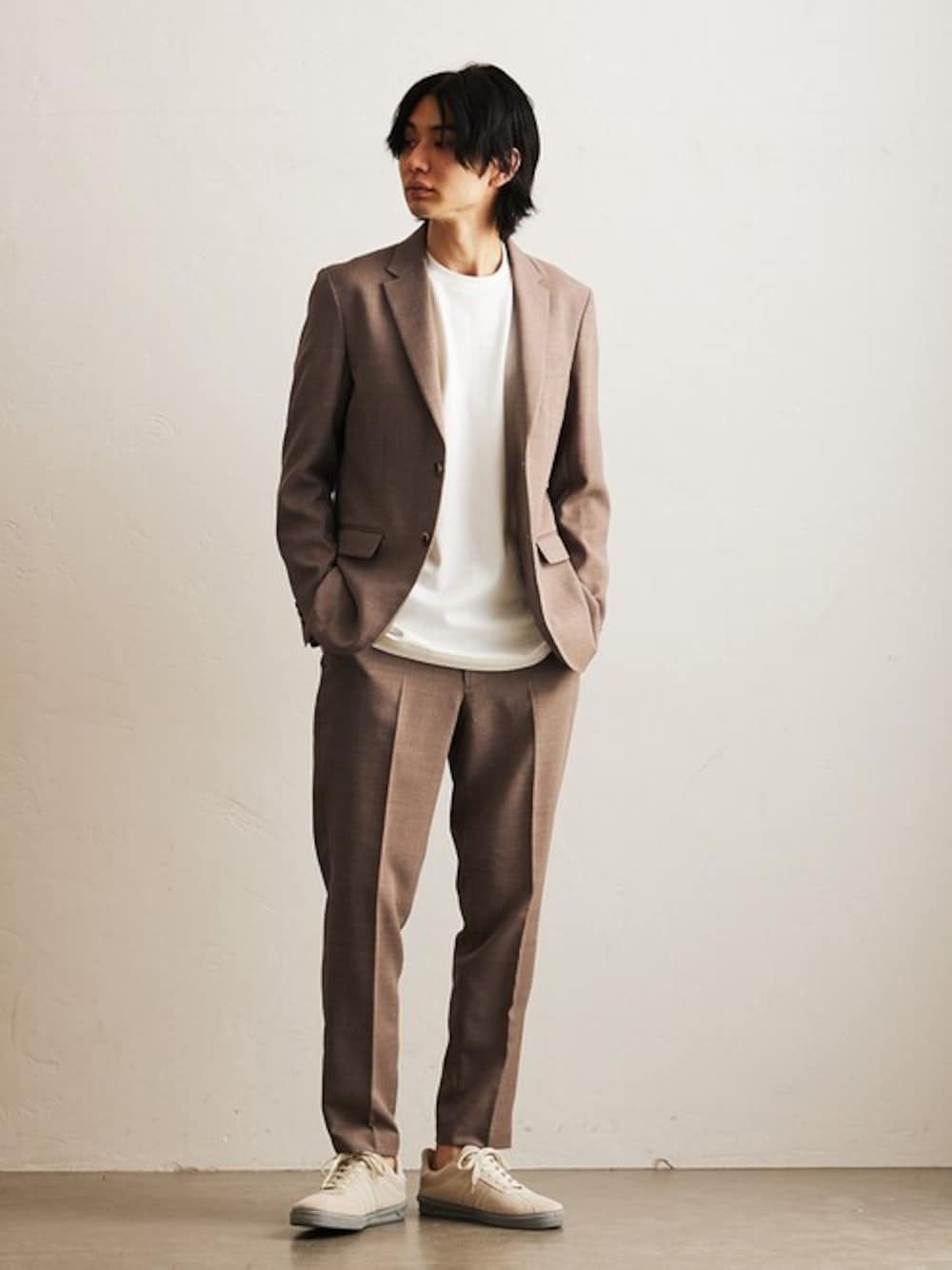 ベージュ系のセットアップ、ホワイト系のTシャツ/カットソー、グレー系のスニーカーを着用したメンズの春コーディネートの1枚目の写真