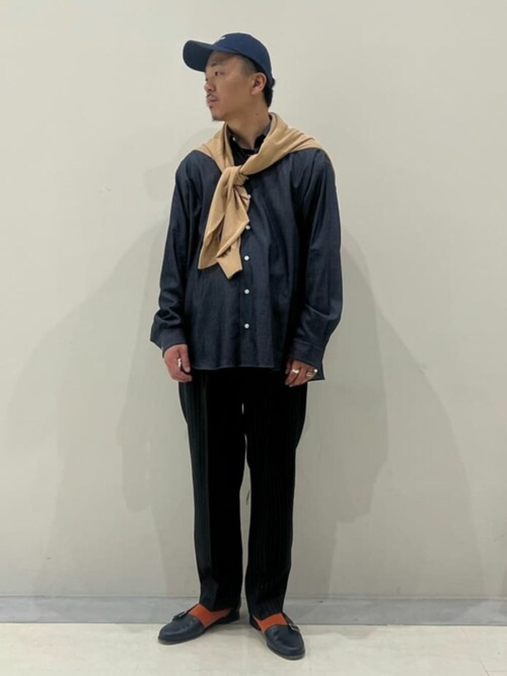 ブルー系のシャツ/ブラウス、ベージュ系のニット/セーター、ブラック系のスラックスを着用したメンズの春コーディネートの1枚目の写真