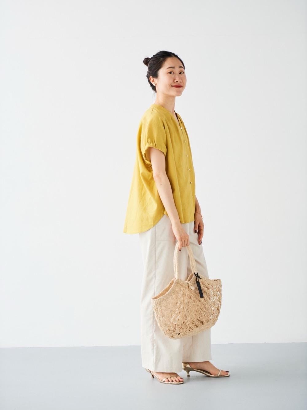 ベージュ系のその他パンツ、ベージュ系のかごバッグ、イエロー系のシャツ/ブラウスを着用したレディースの夏コーディネートの1枚目の写真