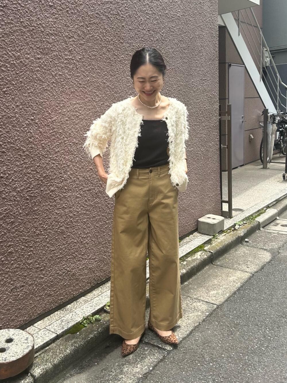 ブラウン系のパンプス、ホワイト系のカーディガン/ボレロ、ベージュ系のチノパンツを着用したレディースの秋コーディネートの1枚目の写真