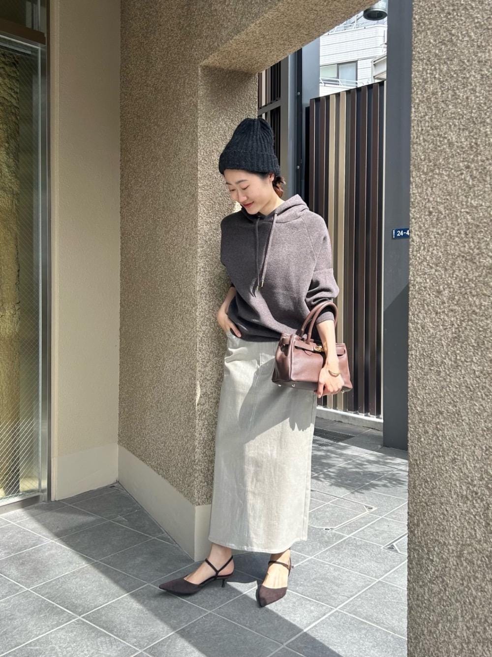 グレー系のニット/セーター、シルバー系のスカートを着用したレディースの秋コーディネートの1枚目の写真