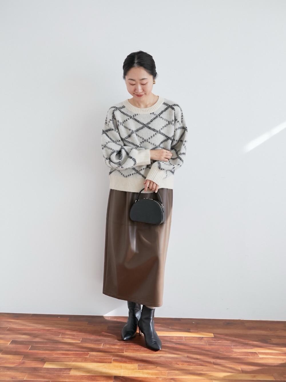 ブラウン系のスカート、ホワイト系のニット/セーターを着用したレディースの冬コーディネートの1枚目の写真