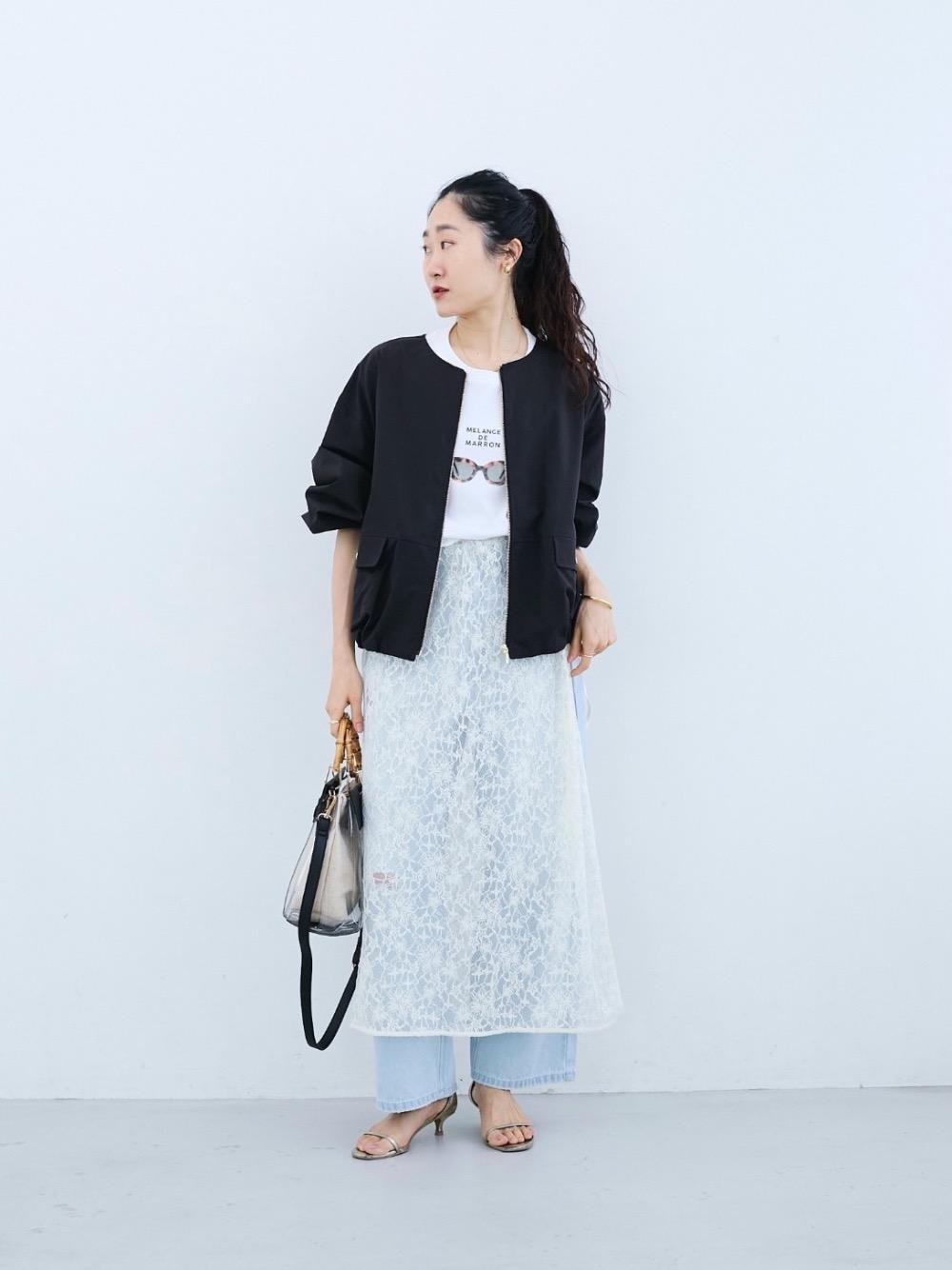 ブルー系のデニムパンツ、ブラック系のハンドバッグ、ホワイト系のスカートを着用したレディースの冬コーディネートの1枚目の写真