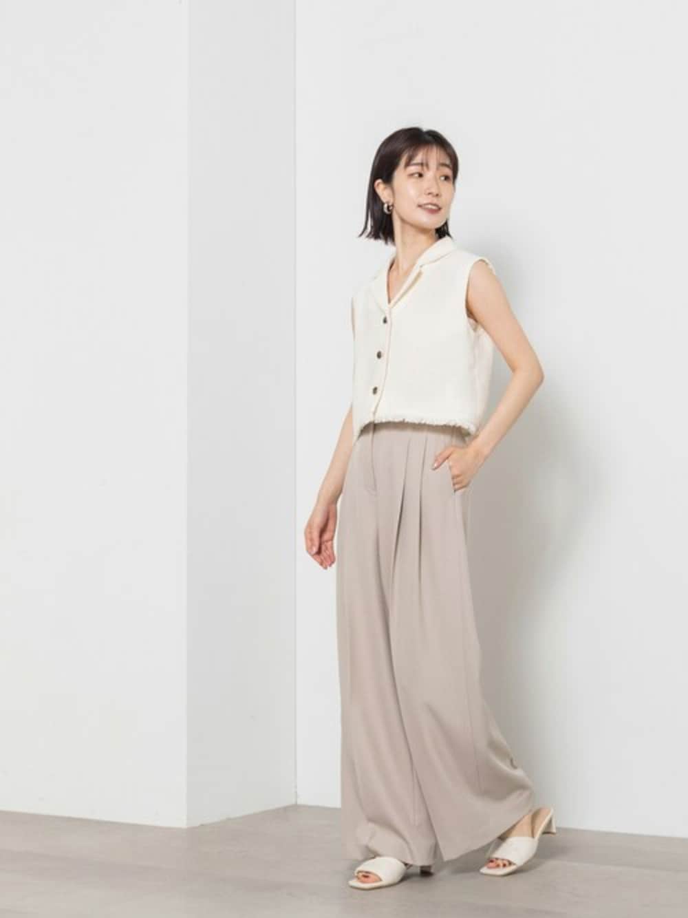 ホワイト系のベスト、ベージュ系のその他パンツ、ホワイト系のサンダルを着用したレディースの夏コーディネートの1枚目の写真
