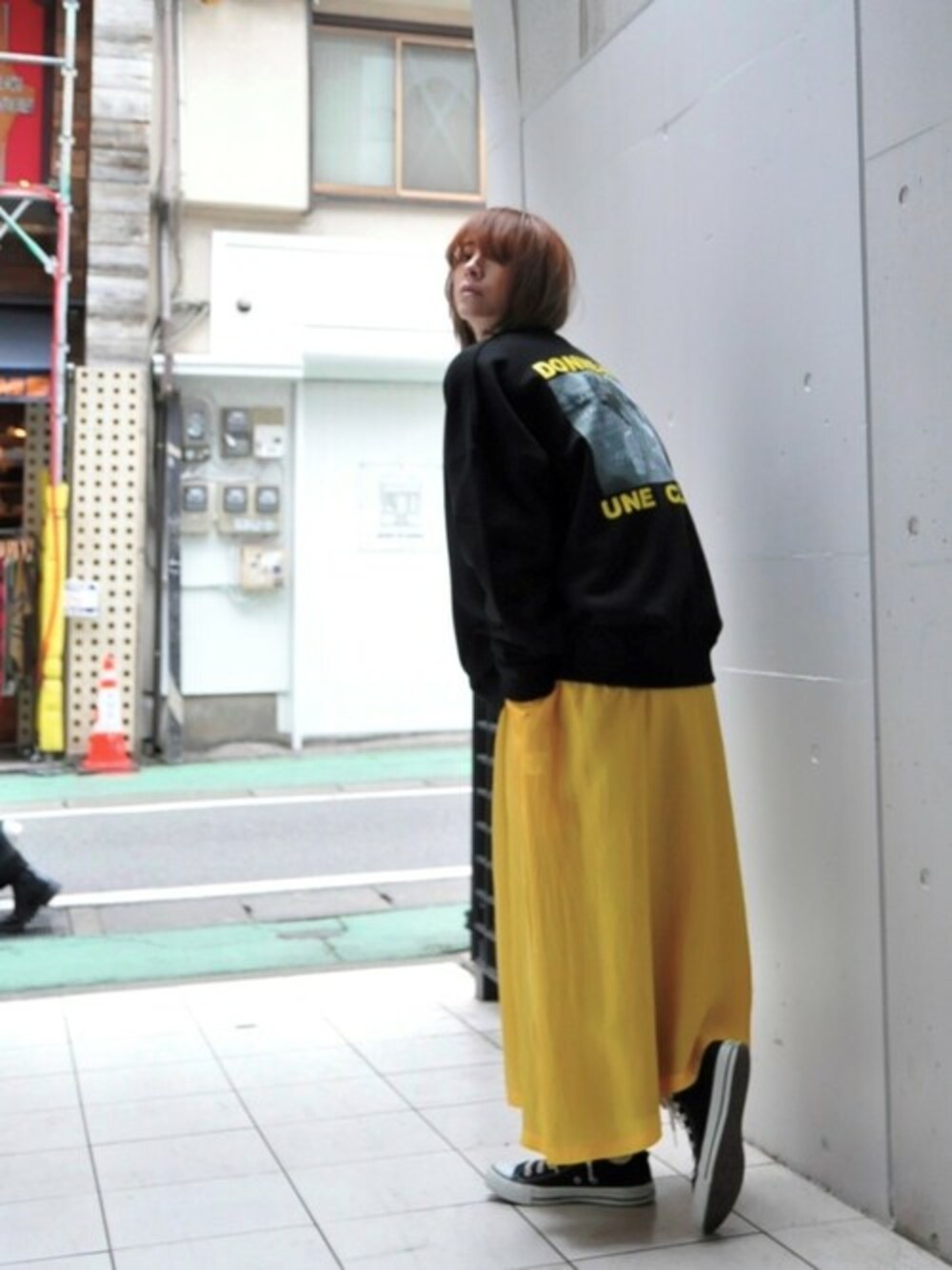 イエロー系のワンピース、ブラック系のスウェットを着用したレディースの春コーディネートの1枚目の写真