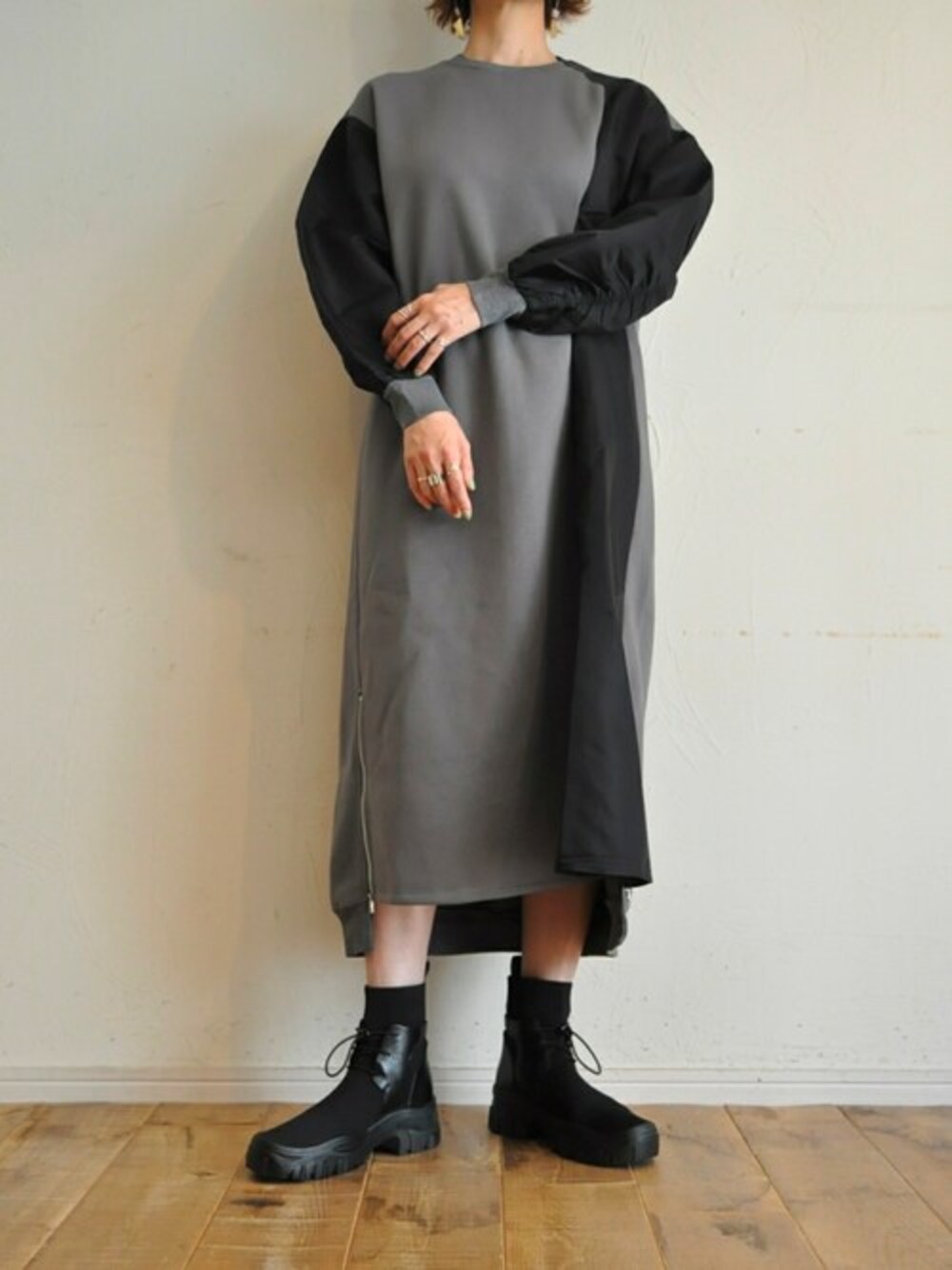 グレー系のワンピース、ブラック系のブーツを着用したレディースの秋コーディネートの1枚目の写真