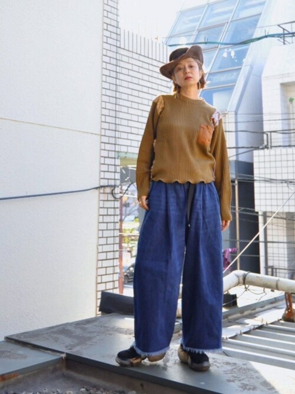 ブラウン系のニット/セーター、ブルー系のデニムパンツを着用したレディースの冬コーディネートの1枚目の写真