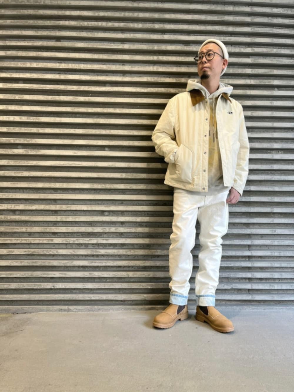 ホワイト系のデニムパンツ、ブラウン系のブーツ、ホワイト系のブルゾンを着用したメンズの秋コーディネートの1枚目の写真