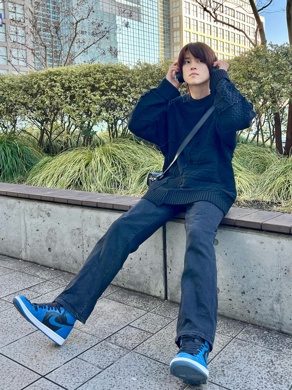 ブルー系のスニーカー、ブラック系のデニムパンツ、ブラック系のショルダーバッグを着用したメンズの冬コーディネートの1枚目の写真