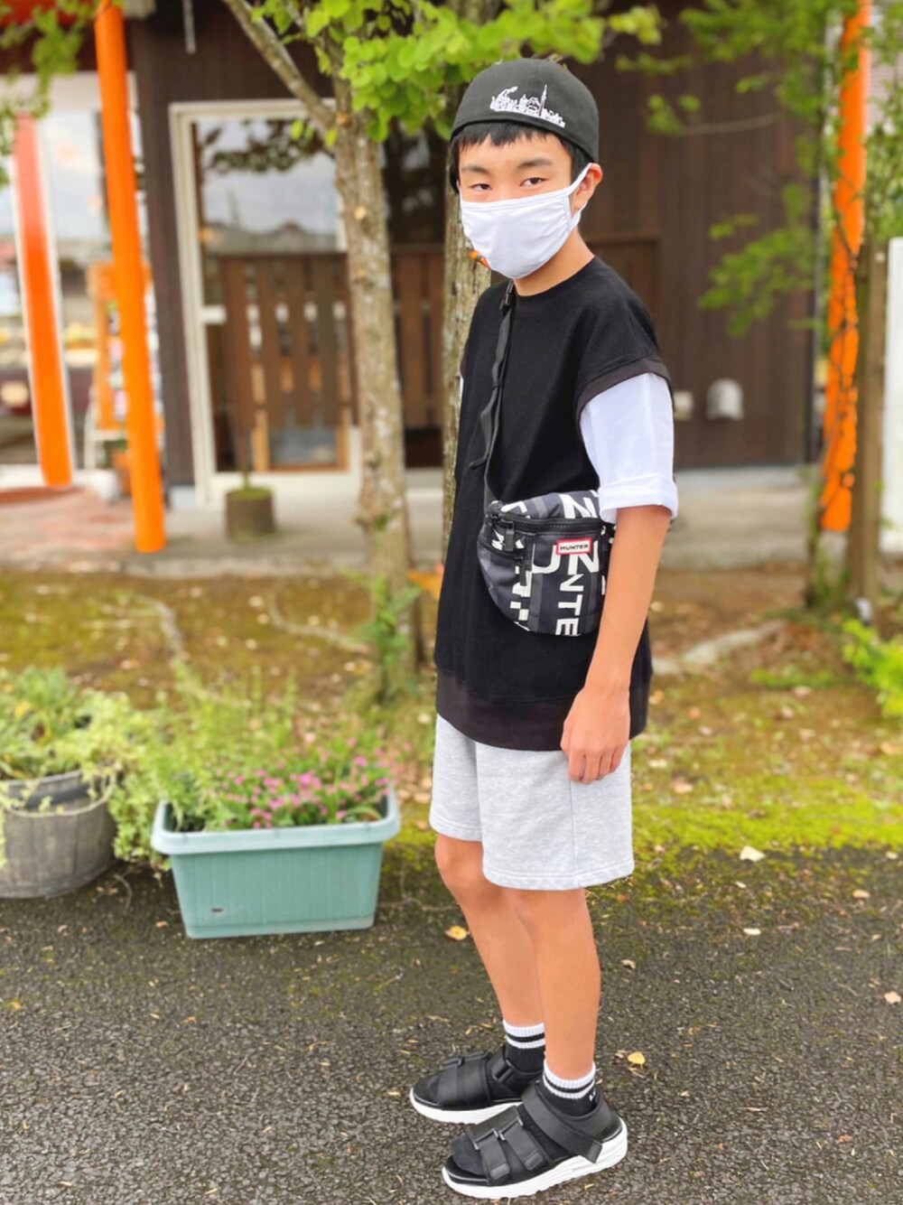 ブラック系のTシャツ/カットソー、ブラック系のボディバッグ/ウエストポーチ、ブラック系のサンダルを着用したキッズの秋コーディネートの1枚目の写真