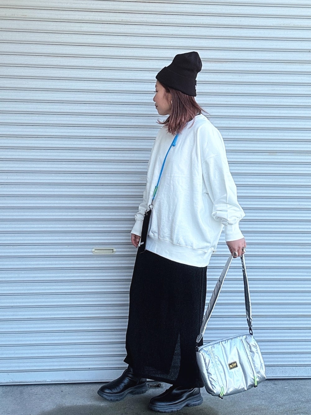 ブラック系のブーツ、シルバー系のショルダーバッグ、ブラック系のスカートを着用したレディースの冬コーディネートの1枚目の写真