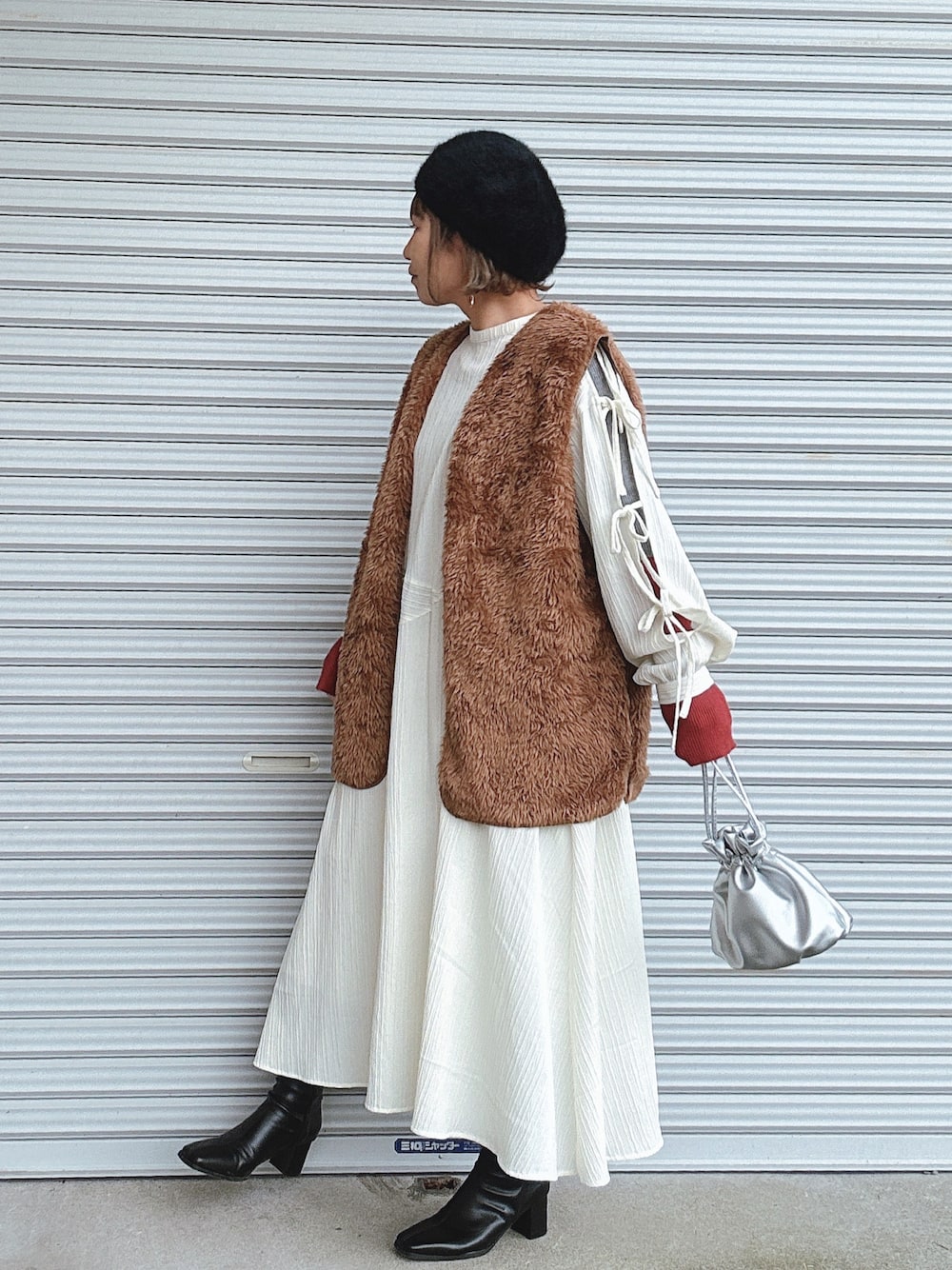 ブラウン系のベスト、ホワイト系のワンピース、グレー系のニット/セーターを着用したレディースの冬コーディネートの1枚目の写真