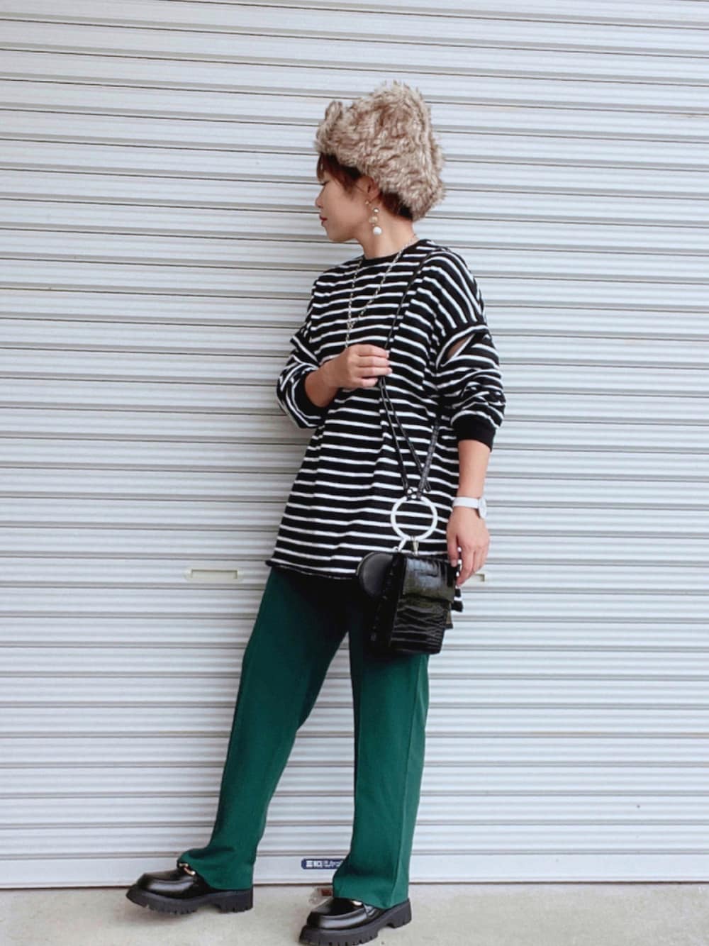 ブラック系のTシャツ/カットソー、ブラック系のバッグ、グリーン系のスラックスを着用したレディースの秋コーディネートの1枚目の写真