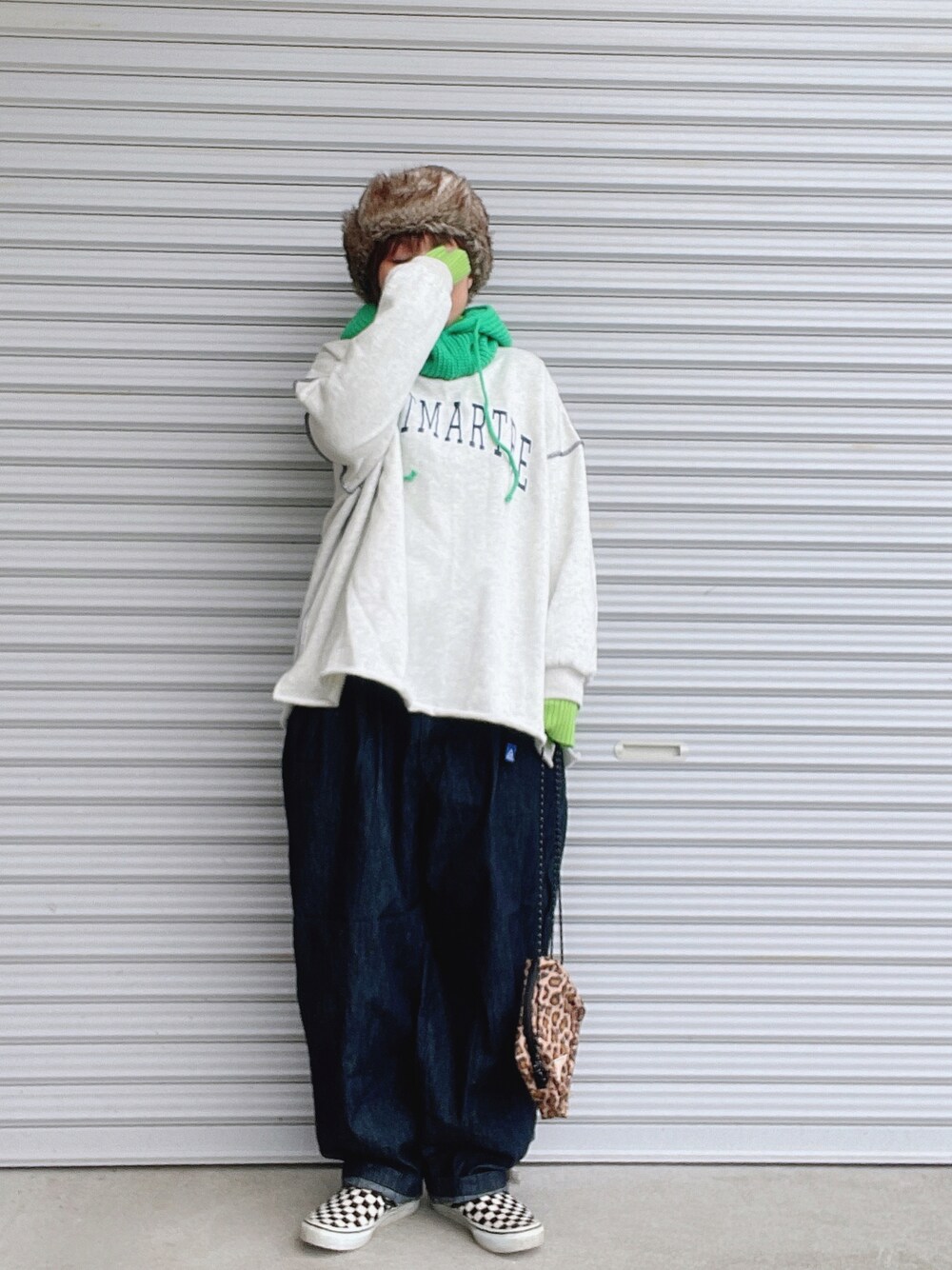 グレー系のスウェット、グリーン系のニット/セーター、ブルー系のデニムパンツを着用したレディースの冬コーディネートの1枚目の写真