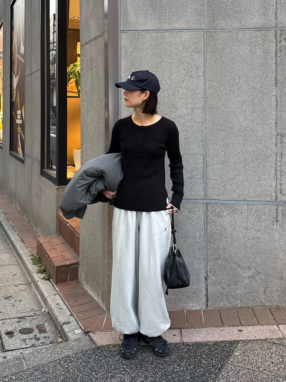 ブラック系のニット/セーター、グレー系のスウェットパンツ、ブラック系のショルダーバッグを着用したレディースの冬コーディネートの1枚目の写真