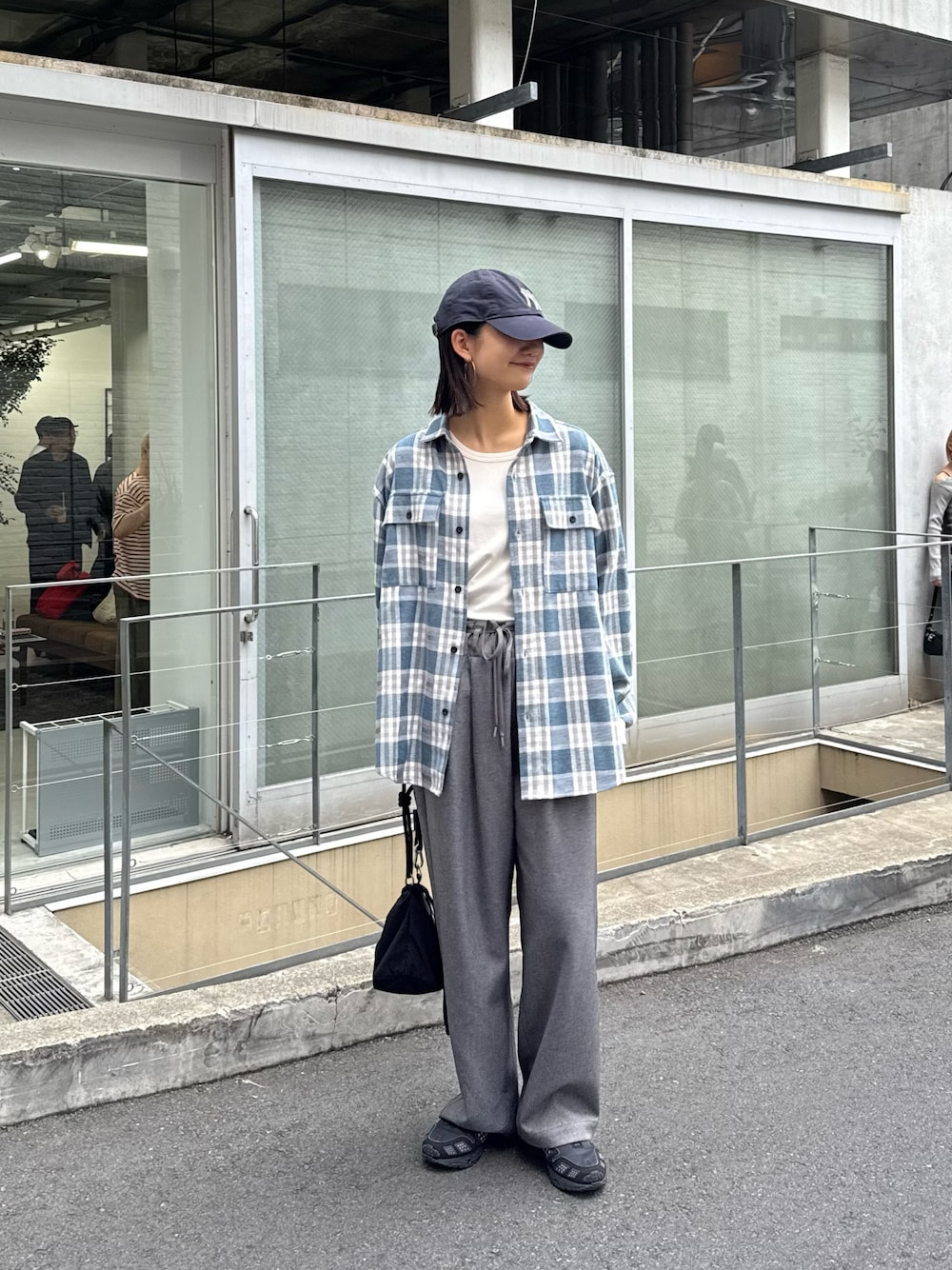 ブルー系のシャツ/ブラウス、グレー系のスラックス、ブラック系のショルダーバッグを着用したレディースの秋コーディネートの1枚目の写真