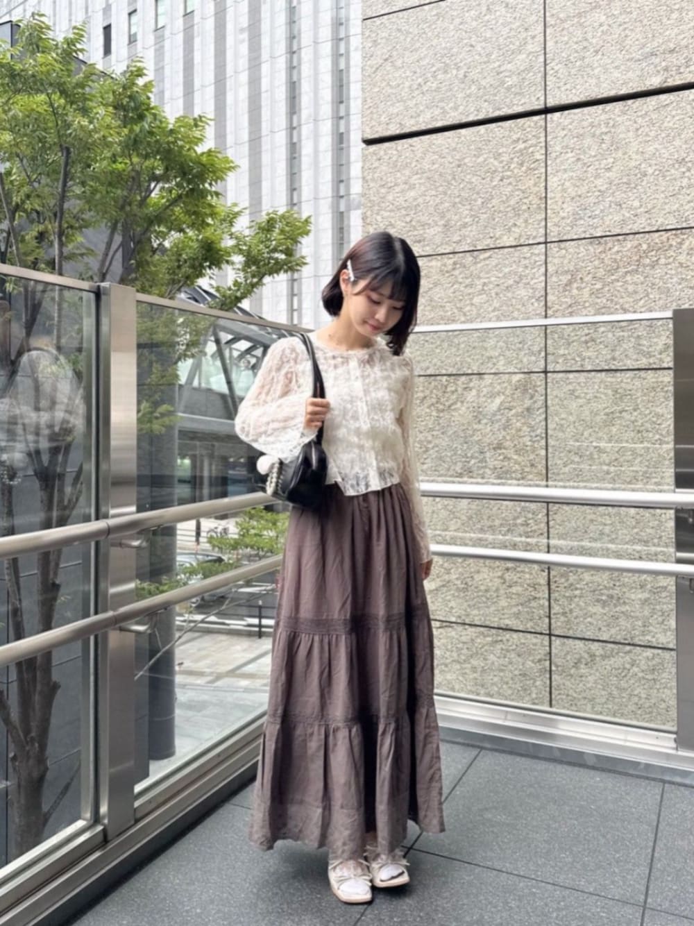 ブラウン系のスカート、ホワイト系のTシャツ/カットソー、ブラック系のショルダーバッグを着用したレディースの秋コーディネートの1枚目の写真