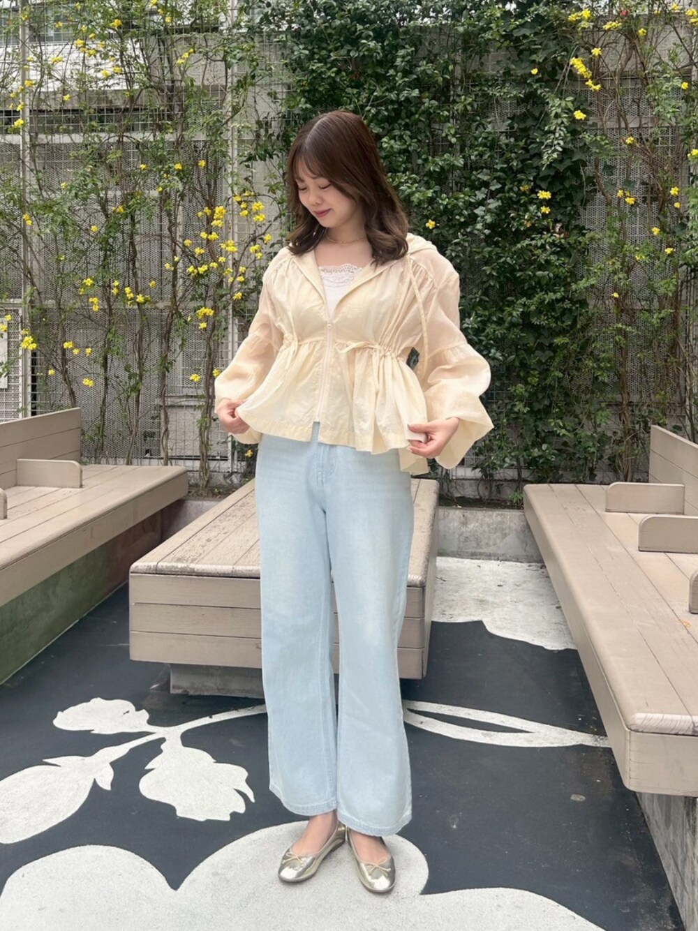 ホワイト系のキャミソール、ベージュ系のナイロンジャケット、ブルー系のデニムパンツを着用したレディースの春コーディネートの1枚目の写真