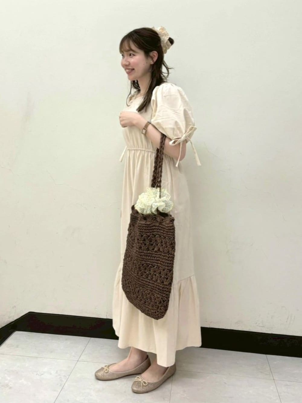 ホワイト系のワンピース、ブラウン系のトートバッグ、ゴールド系のバレエシューズを着用したレディースの夏コーディネートの1枚目の写真