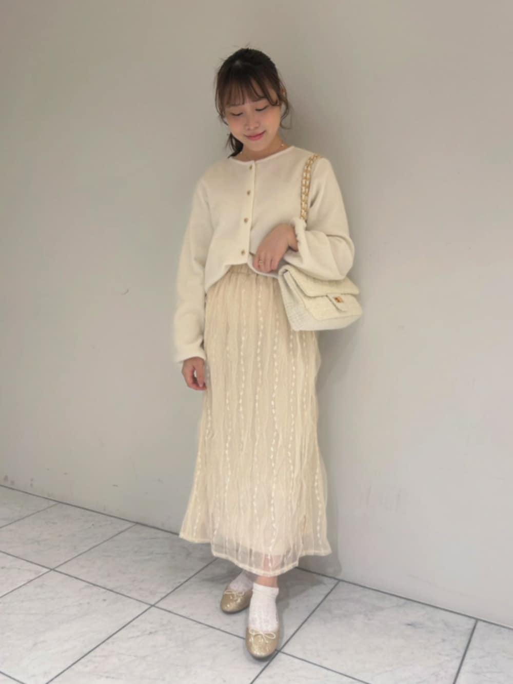 ホワイト系のカーディガン/ボレロ、ホワイト系のショルダーバッグ、ホワイト系のスカートを着用したレディースの秋コーディネートの1枚目の写真
