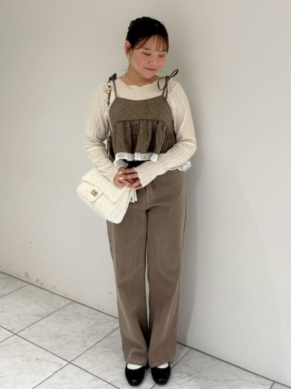 ホワイト系のTシャツ/カットソー、ブラウン系のキャミソール、ブラウン系のデニムパンツを着用したレディースの秋コーディネートの1枚目の写真