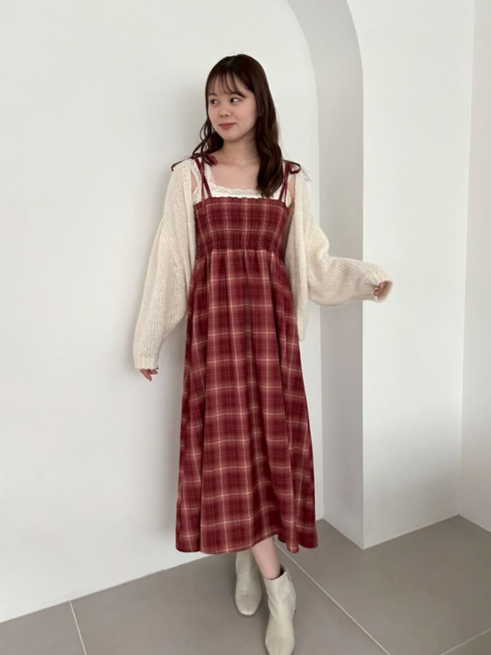 ホワイト系のカーディガン/ボレロ、レッド系のワンピース、ホワイト系のブーツを着用したレディースの秋コーディネートの1枚目の写真
