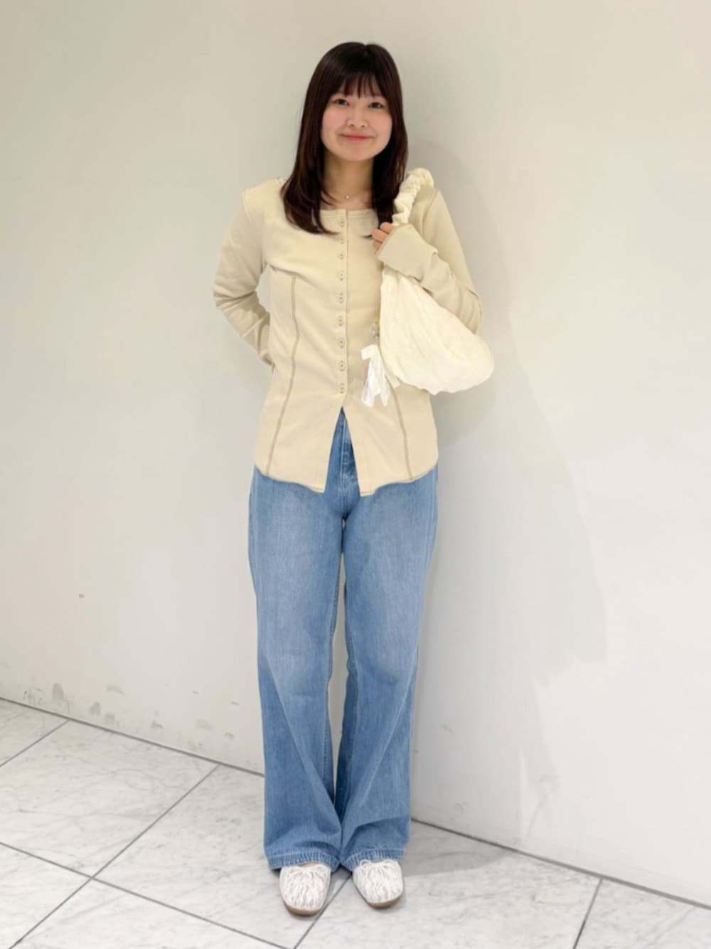 ブルー系のデニムパンツ、ホワイト系のショルダーバッグ、ホワイト系のカーディガン/ボレロを着用したレディースの秋コーディネートの1枚目の写真