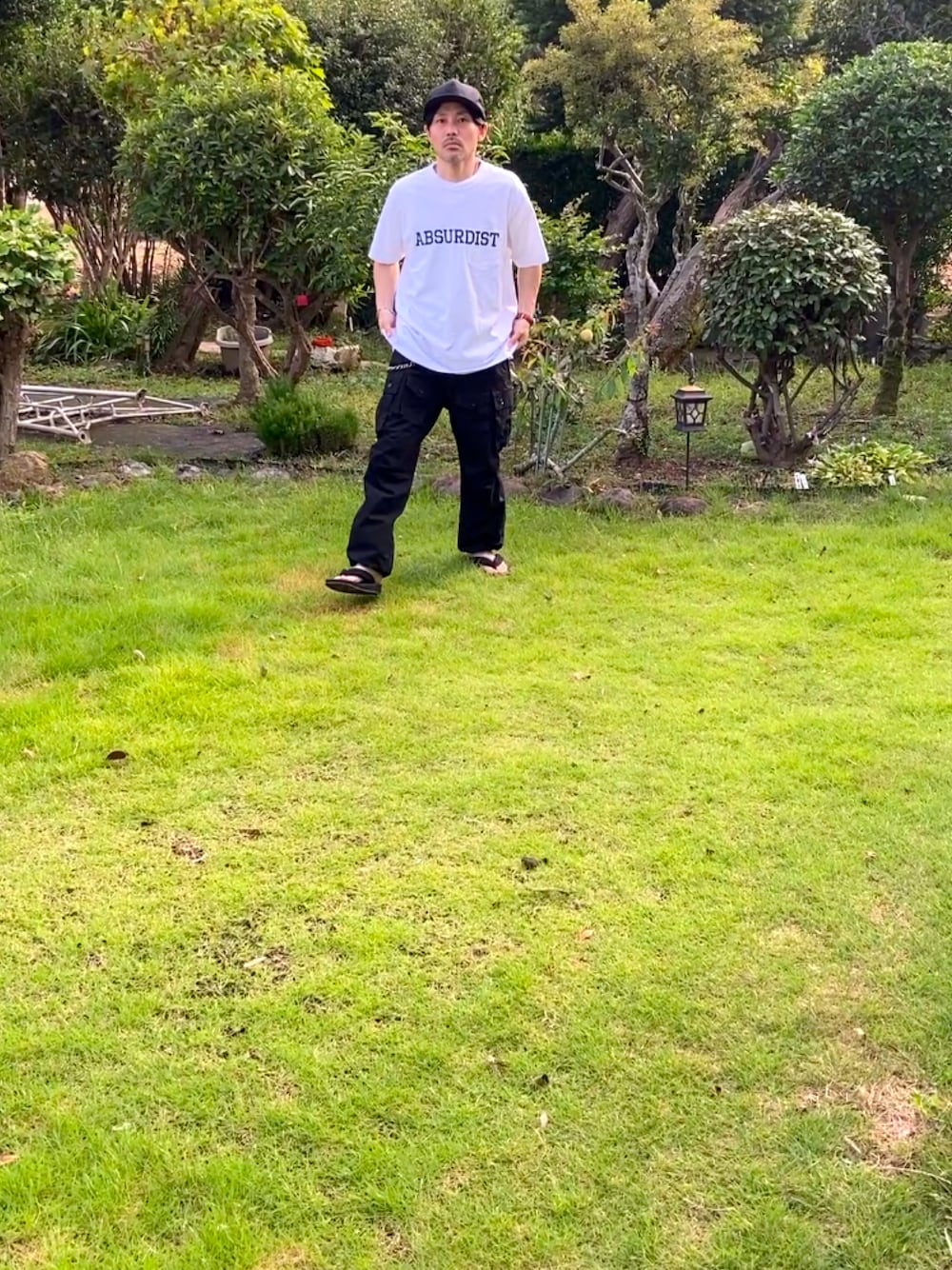 ホワイト系のTシャツ/カットソー、ブラック系のカーゴパンツ、ブラック系のサンダルを着用したメンズの夏コーディネートの1枚目の写真