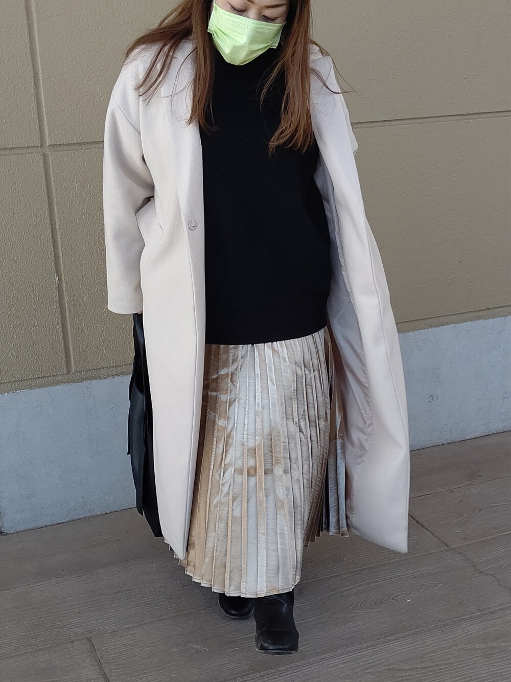 ゴールド系のスカート、ブラック系のニット/セーター、ブラック系のバッグを着用したレディースの冬コーディネートの2枚目の写真