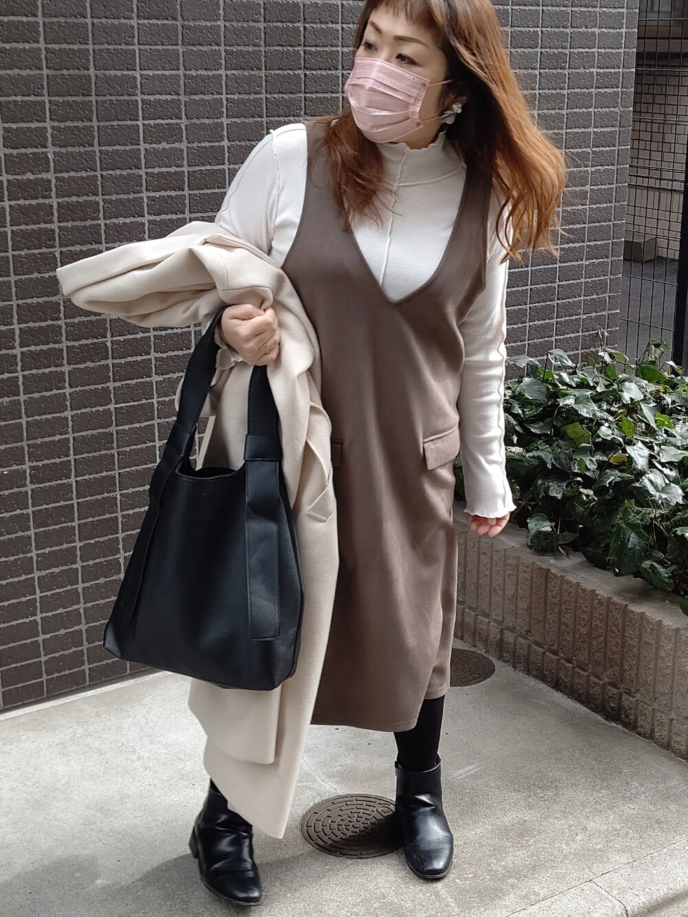 ホワイト系のチェスターコート、ブラック系のバッグ、ホワイト系のTシャツ/カットソーを着用したレディースの冬コーディネートの2枚目の写真