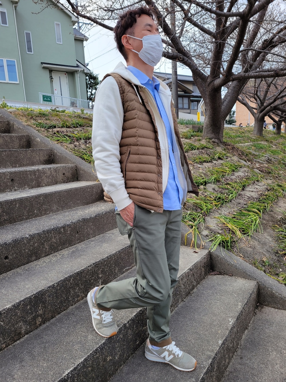 ブルー系のシャツ/ブラウス、イエロー系のダウンベスト、ホワイト系のパーカーを着用したメンズの春コーディネートの2枚目の写真