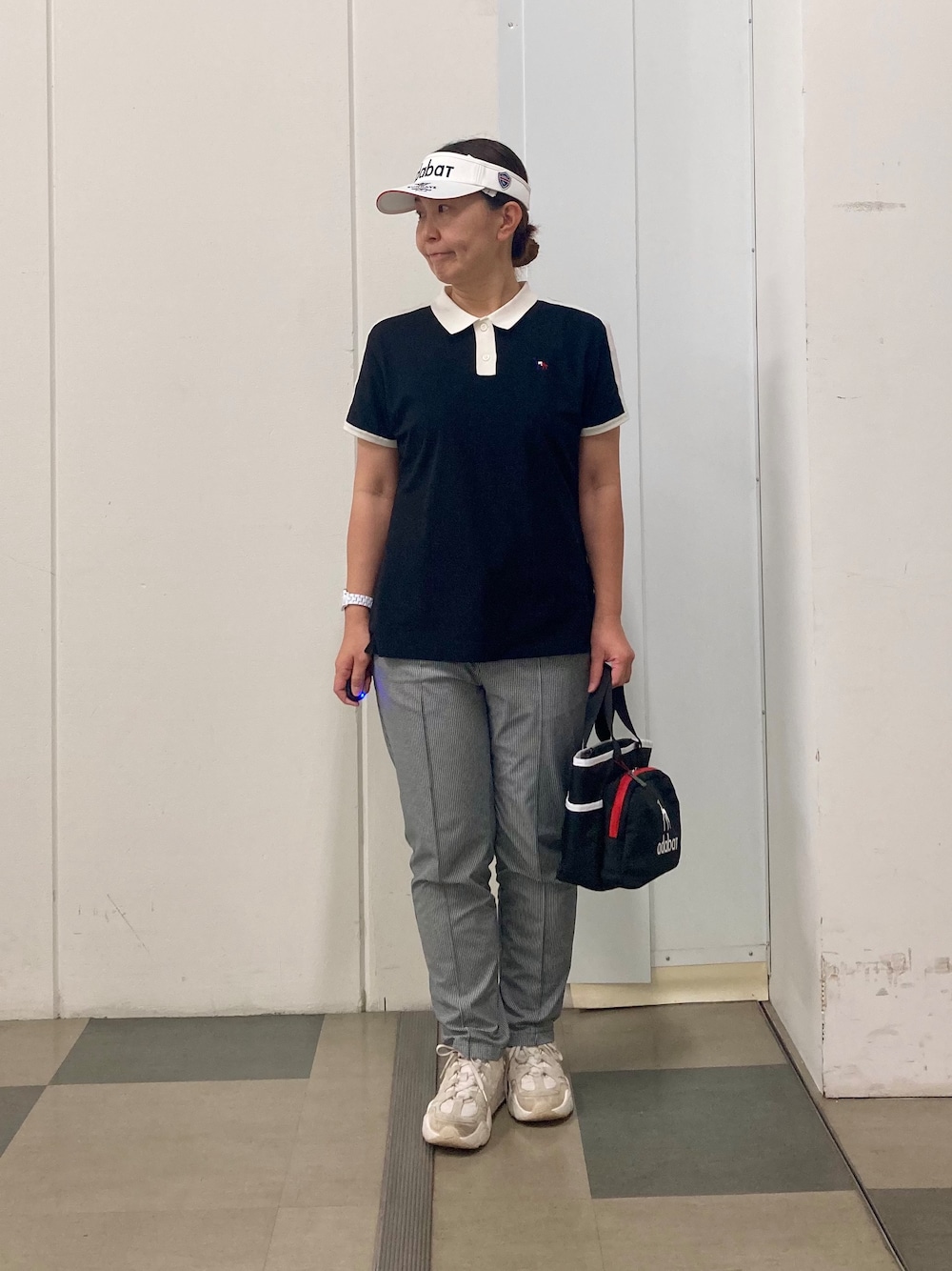 ブラック系のポロシャツ、ブラック系のその他パンツ、ブルー系のトートバッグを着用したレディースの春コーディネートの1枚目の写真