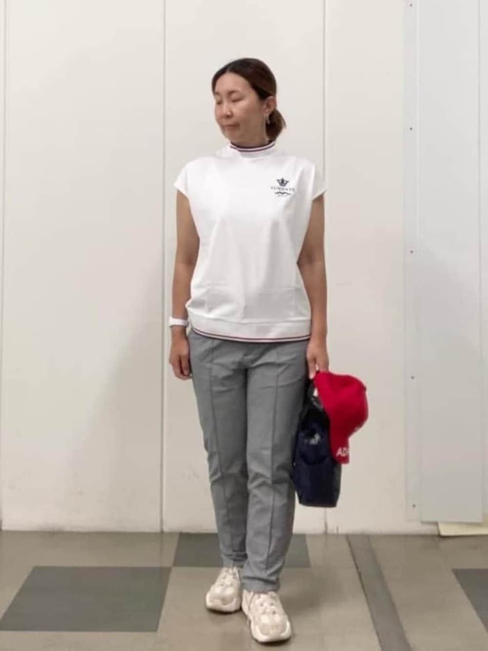 ブルー系のハンドバッグ、レッド系のキャップを着用したレディースの春コーディネートの1枚目の写真