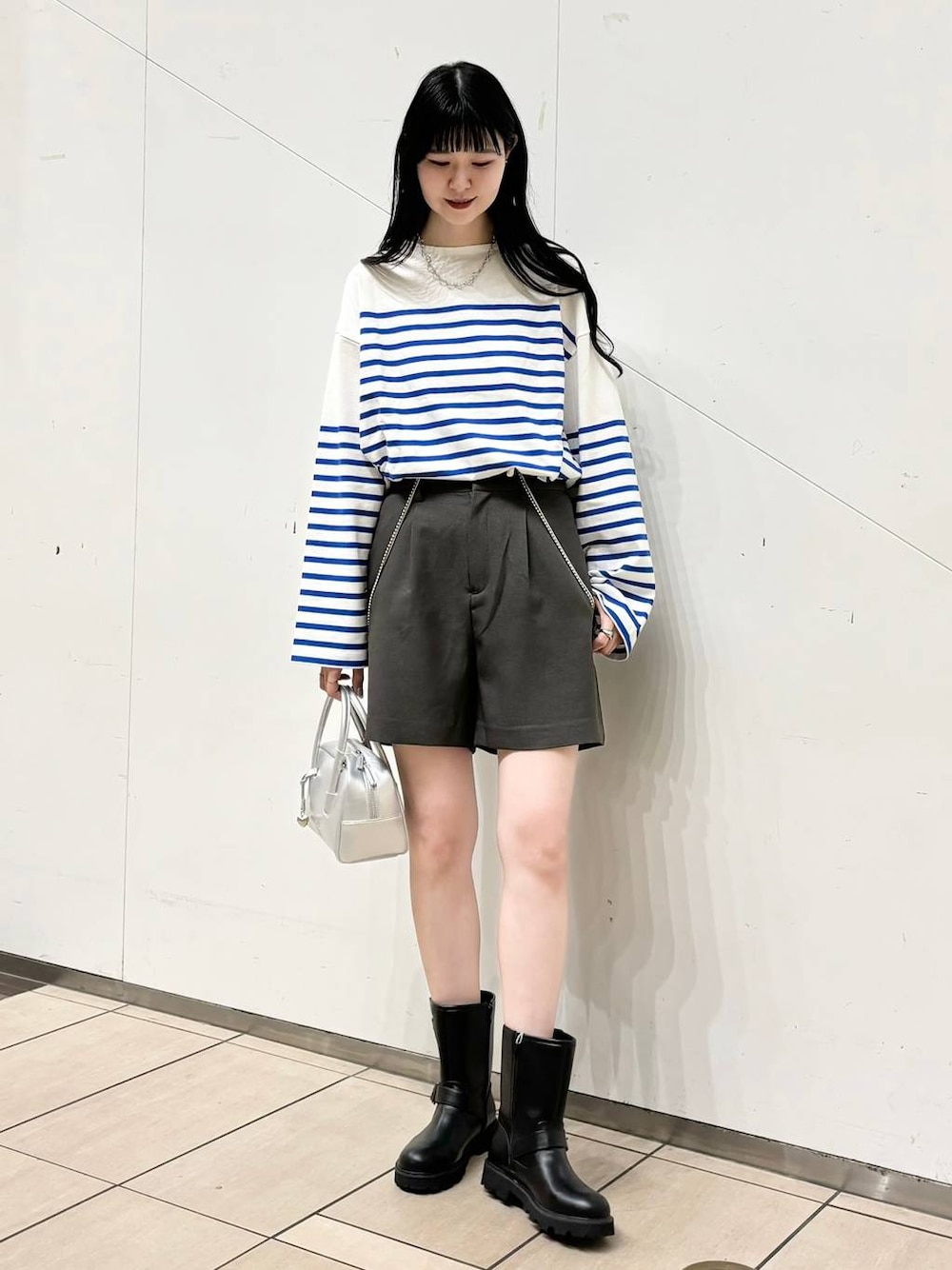 ブラック系のブーツ、シルバー系のボストンバッグ、グレー系のその他パンツを着用したレディースの秋コーディネートの1枚目の写真