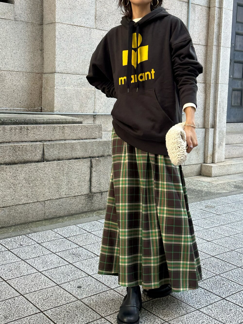 イエロー系のスウェット、ブラウン系のスカート、ブラック系のブーツを着用したレディースの秋コーディネートの1枚目の写真