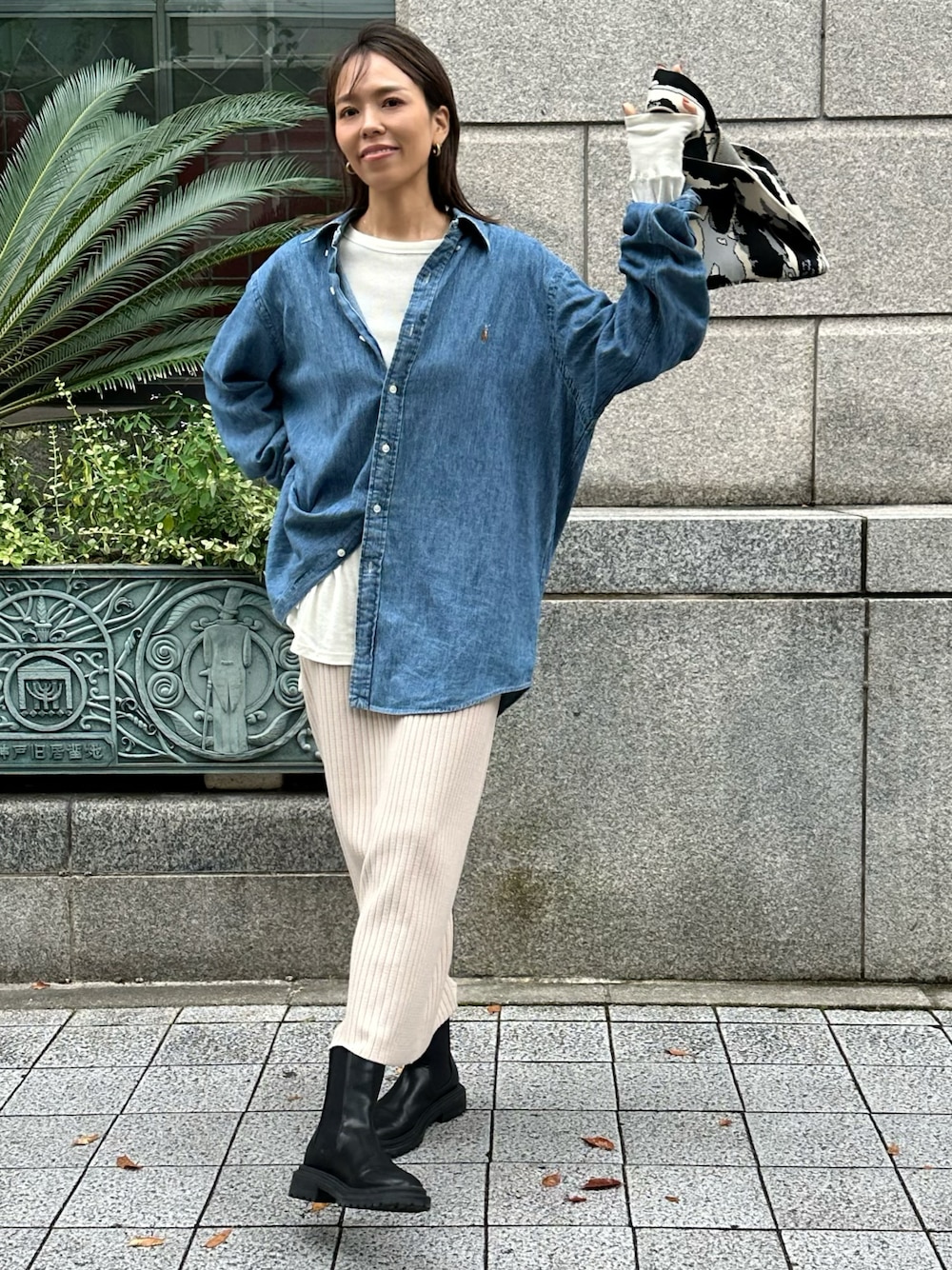 ベージュ系のスカート、ブラック系のブーツ、ブラック系のトートバッグを着用したレディースの秋コーディネートの1枚目の写真