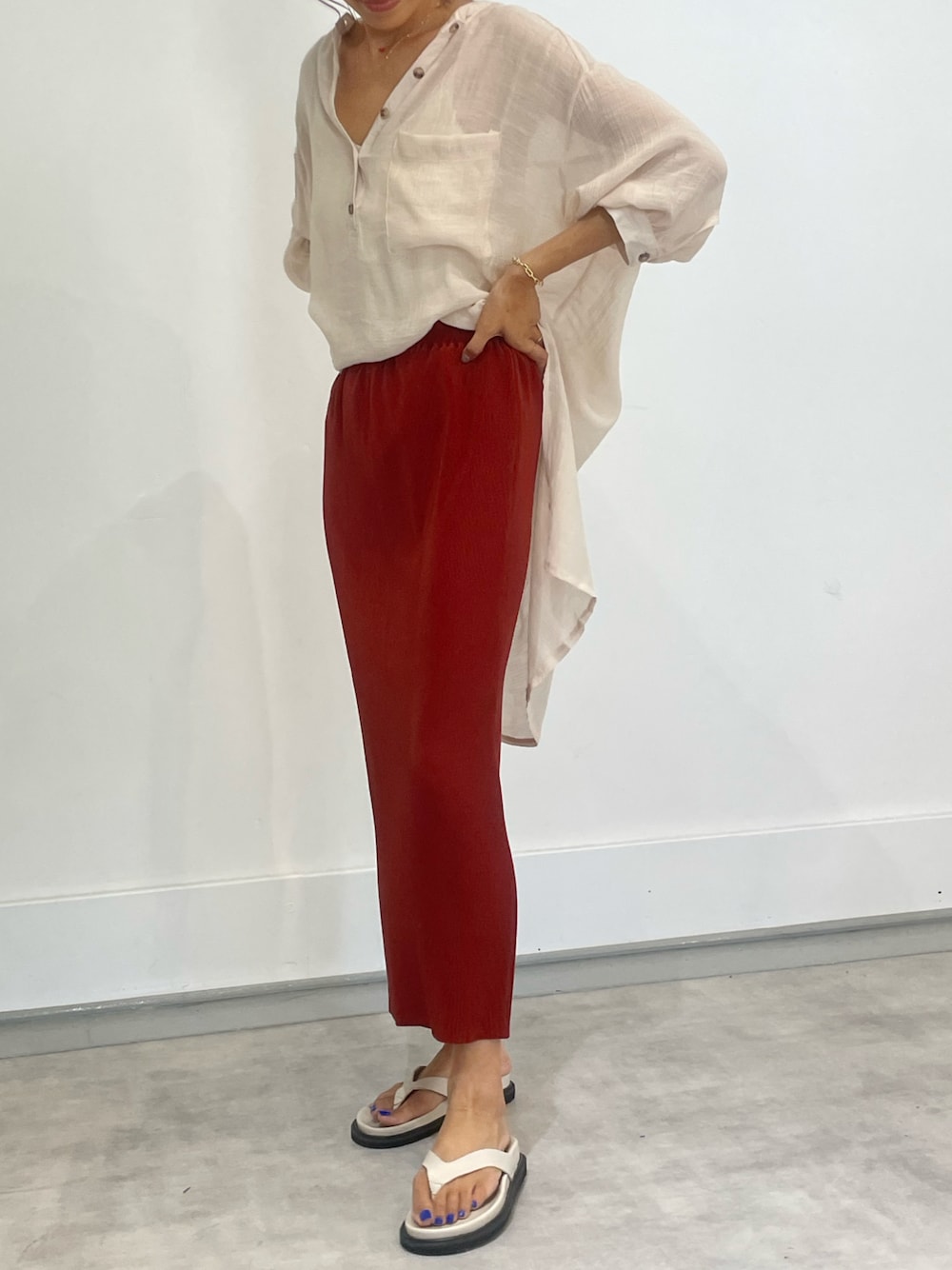 レッド系のスカート、ベージュ系のシャツ/ブラウス、ホワイト系のサンダルを着用したレディースの夏コーディネートの1枚目の写真