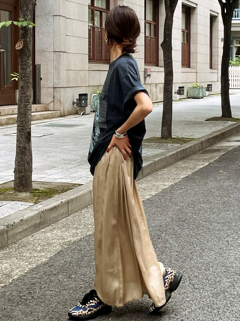 ゴールド系のスカート、ブラック系のTシャツ/カットソーを着用したレディースの春コーディネートの1枚目の写真