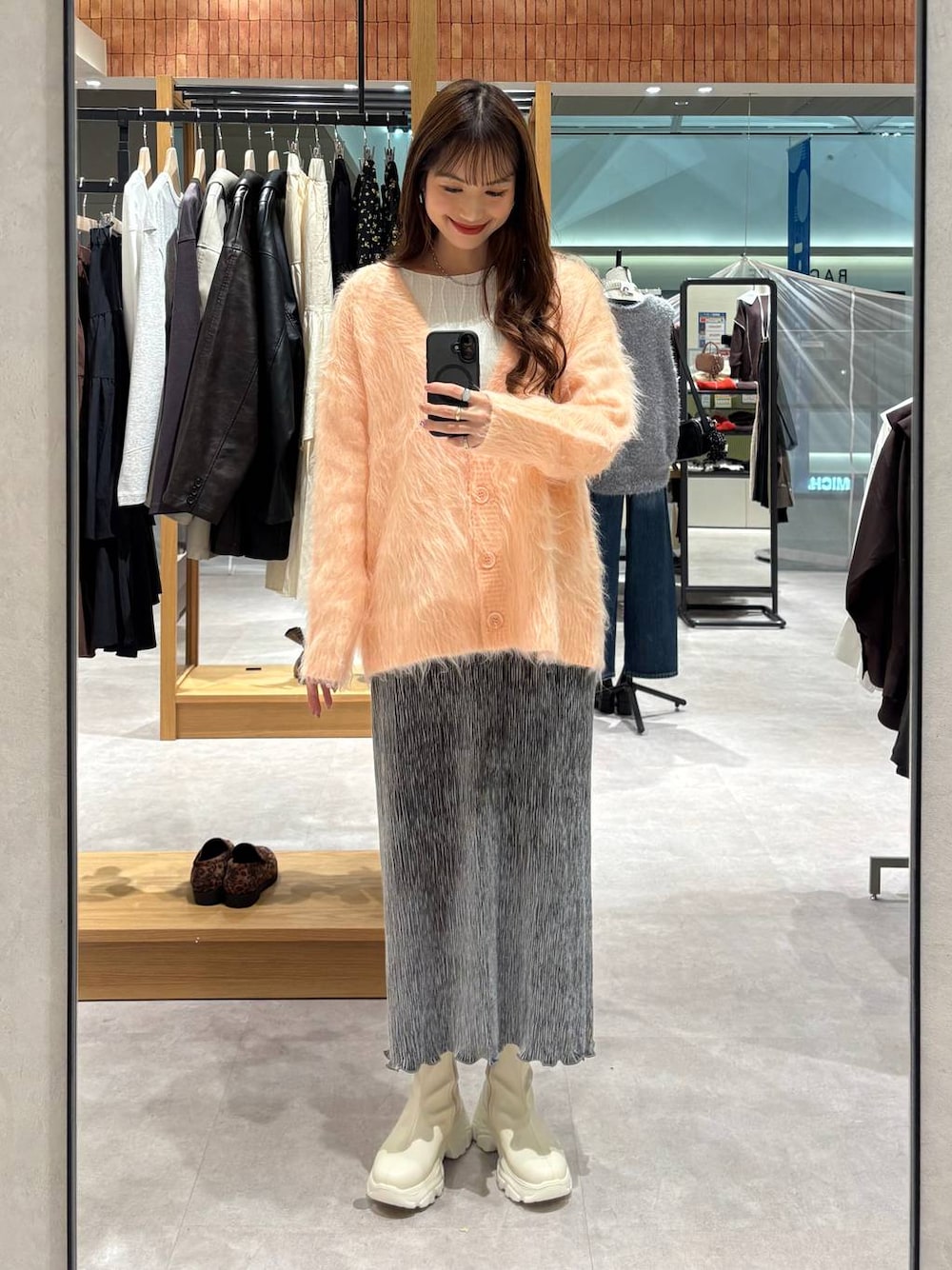 ベージュ系のTシャツ/カットソー、ホワイト系のブーツ、グレー系のスカートを着用したレディースの秋コーディネートの1枚目の写真