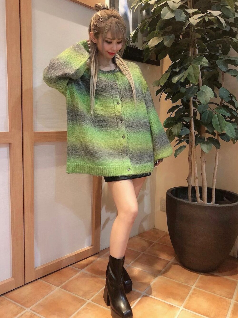 グリーン系のカーディガン/ボレロ、ブラック系のスカートを着用したレディースの秋コーディネートの1枚目の写真