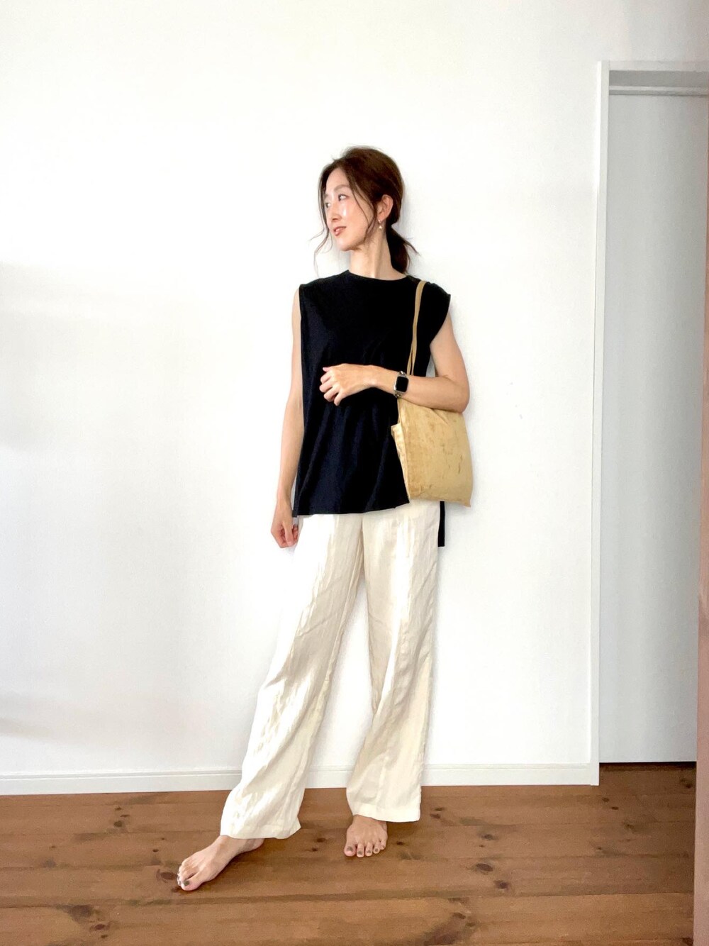 イエロー系のトートバッグ、ホワイト系のパンツ、ブラック系のタンクトップを着用したレディースの夏コーディネートの1枚目の写真