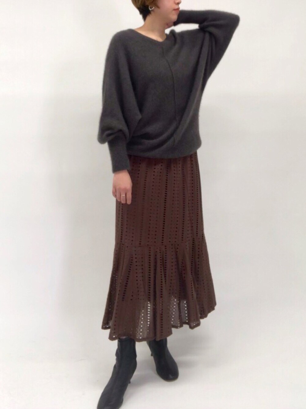 ブラック系のブーツ、ブラウン系のスカート、グレー系のニット/セーターを着用したレディースの秋コーディネートの1枚目の写真