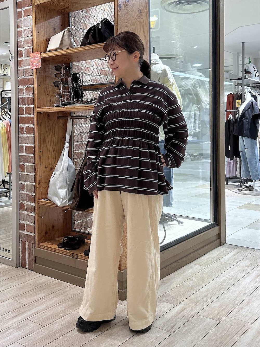 ブラウン系のポロシャツ、ホワイト系のデニムパンツ、ブラック系のローファーを着用したレディースの秋コーディネートの1枚目の写真