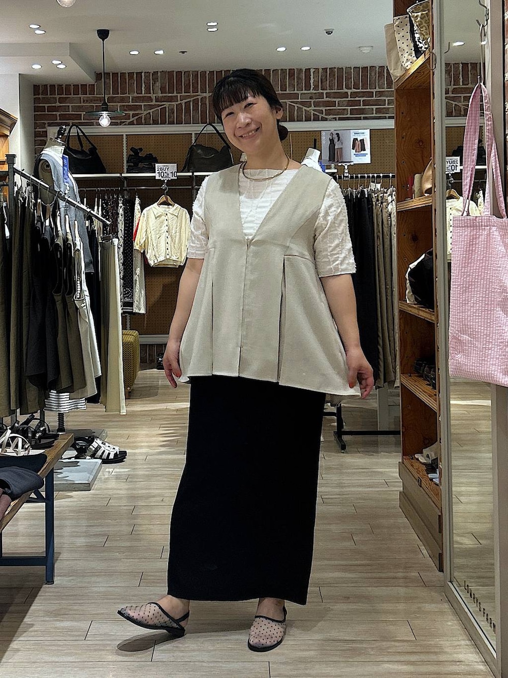 ブラック系のスカート、ホワイト系のTシャツ/カットソー、ベージュ系のベストを着用したレディースの夏コーディネートの1枚目の写真