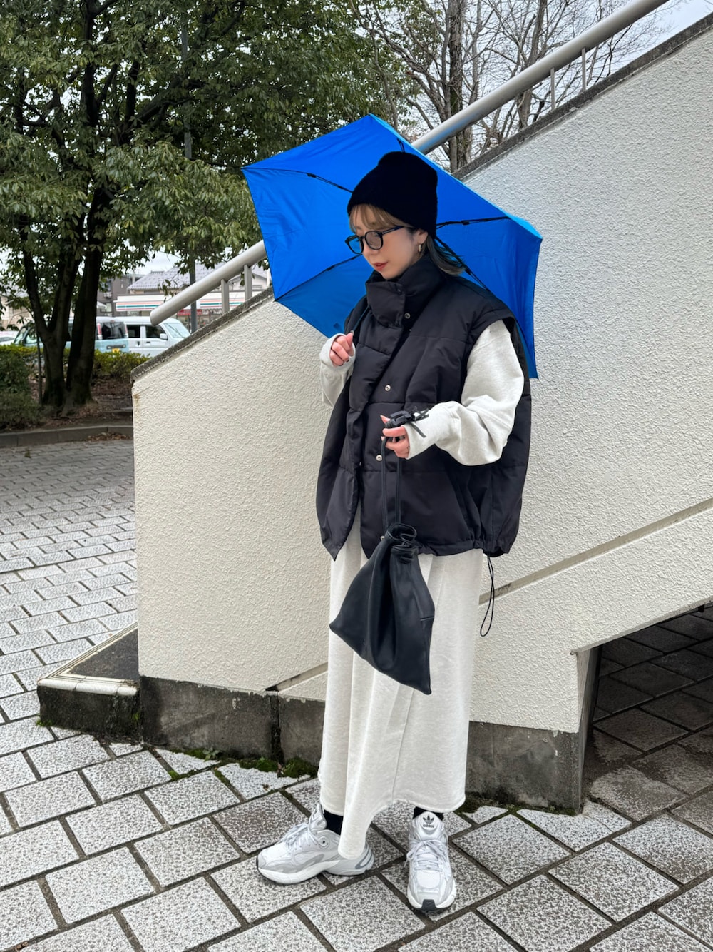 グレー系のスニーカー、ブルー系の折りたたみ傘を着用したレディースの冬コーディネートの1枚目の写真