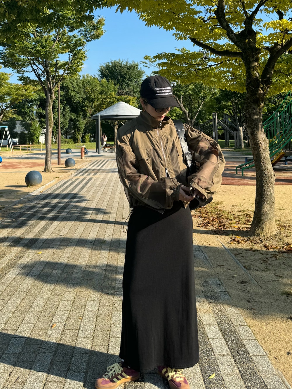 レッド系のスニーカー、ブラック系のハンドバッグ、ブラック系のワンピースを着用したレディースの秋コーディネートの1枚目の写真