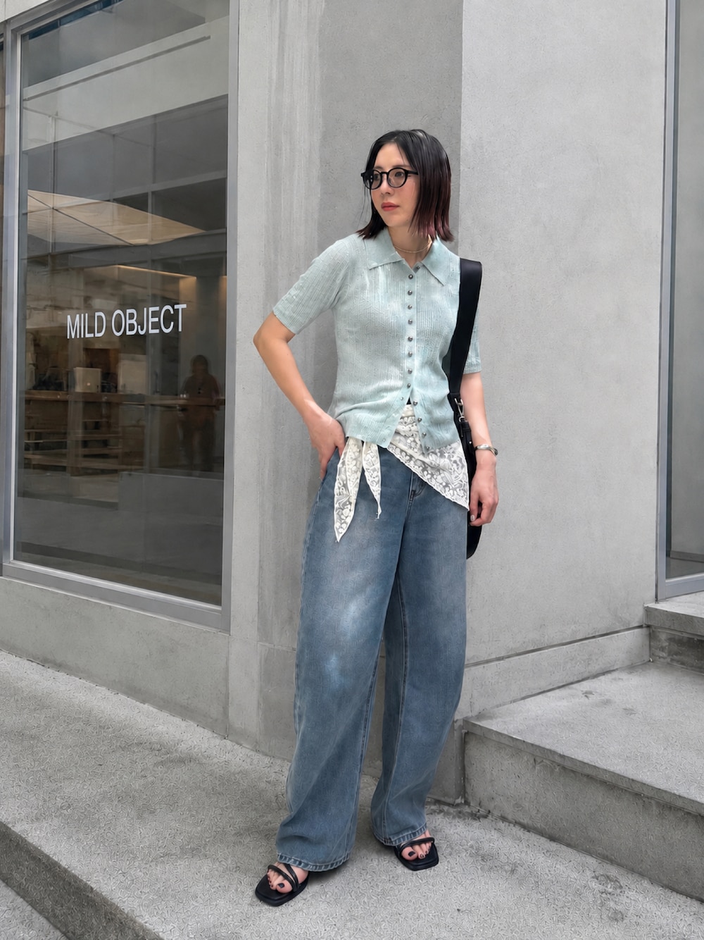 ブルー系のデニムパンツ、ブルー系のニット/セーター、ブラック系のショルダーバッグを着用したレディースの夏コーディネートの1枚目の写真