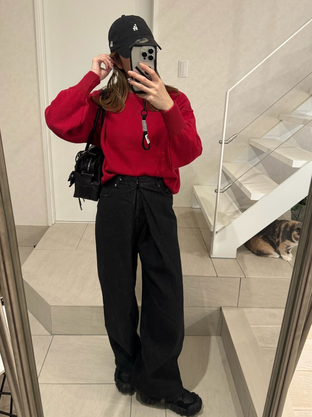 レッド系のニット/セーター、ブラック系のデニムパンツ、ブラック系のボストンバッグを着用したレディースの冬コーディネートの1枚目の写真