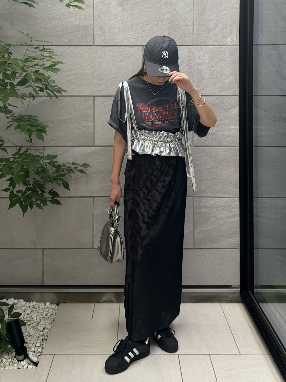 ブラック系のスカート、ブラック系のスニーカー、グレー系のTシャツ/カットソーを着用したレディースの夏コーディネートの1枚目の写真